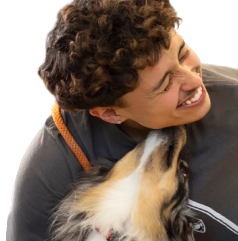 A Dogtopia team member laughing with a dog